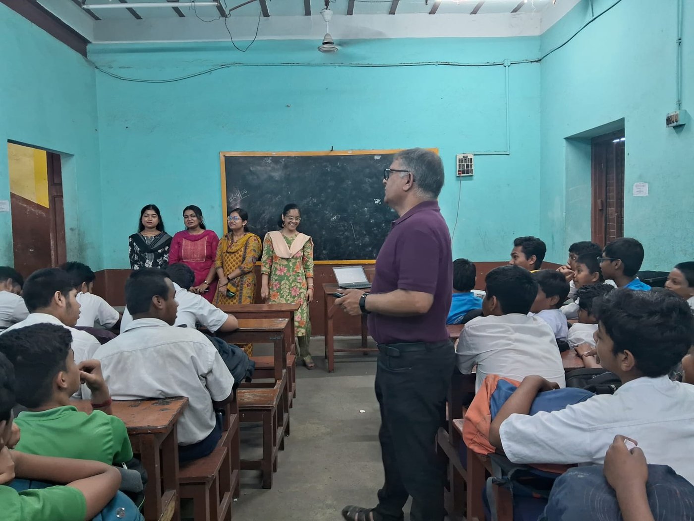 A packed government classroom mid-session, every bench full